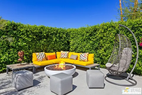 a room with lots of potted plants couches and a fireplace
