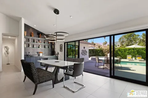 a dining room with furniture a chandelier and glass door