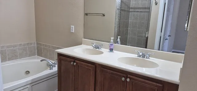 a bathroom with a granite countertop sink a mirror a bathtub and shower