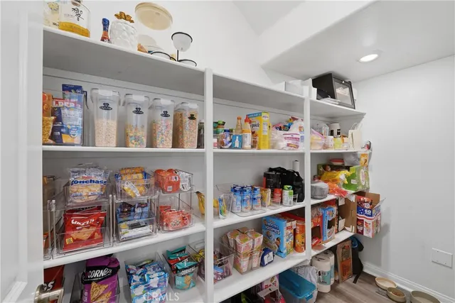 a kitchen with stainless steel appliances kitchen island granite countertop a stove a sink a refrigerator and white cabinets with wooden floor