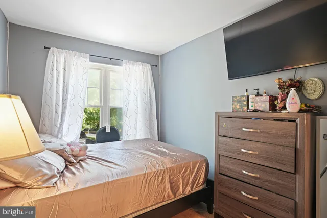 a bedroom with a bed and a flat tv screen on dresser