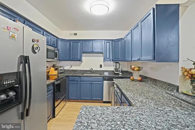 a kitchen with granite countertop a refrigerator a stove and wooden cabinets