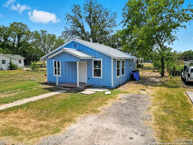 a view of a house with a yard and large tree