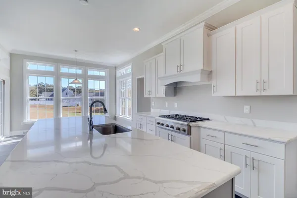 a kitchen with stainless steel appliances granite countertop a stove a sink and white cabinets