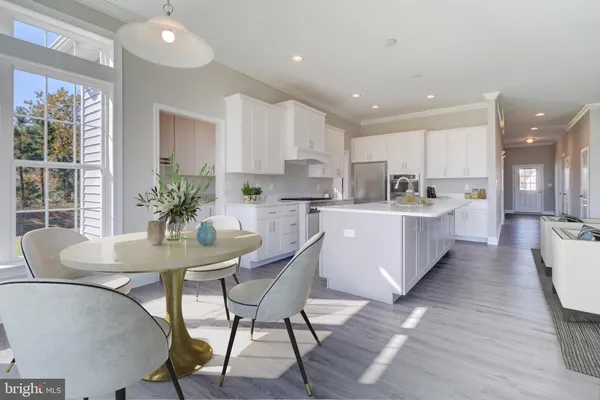 a large white dining hall with stainless steel appliances kitchen island granite countertop a dining table chairs and a large window