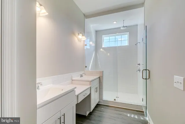 a spacious bathroom with a double vanity sink a mirror and a shower