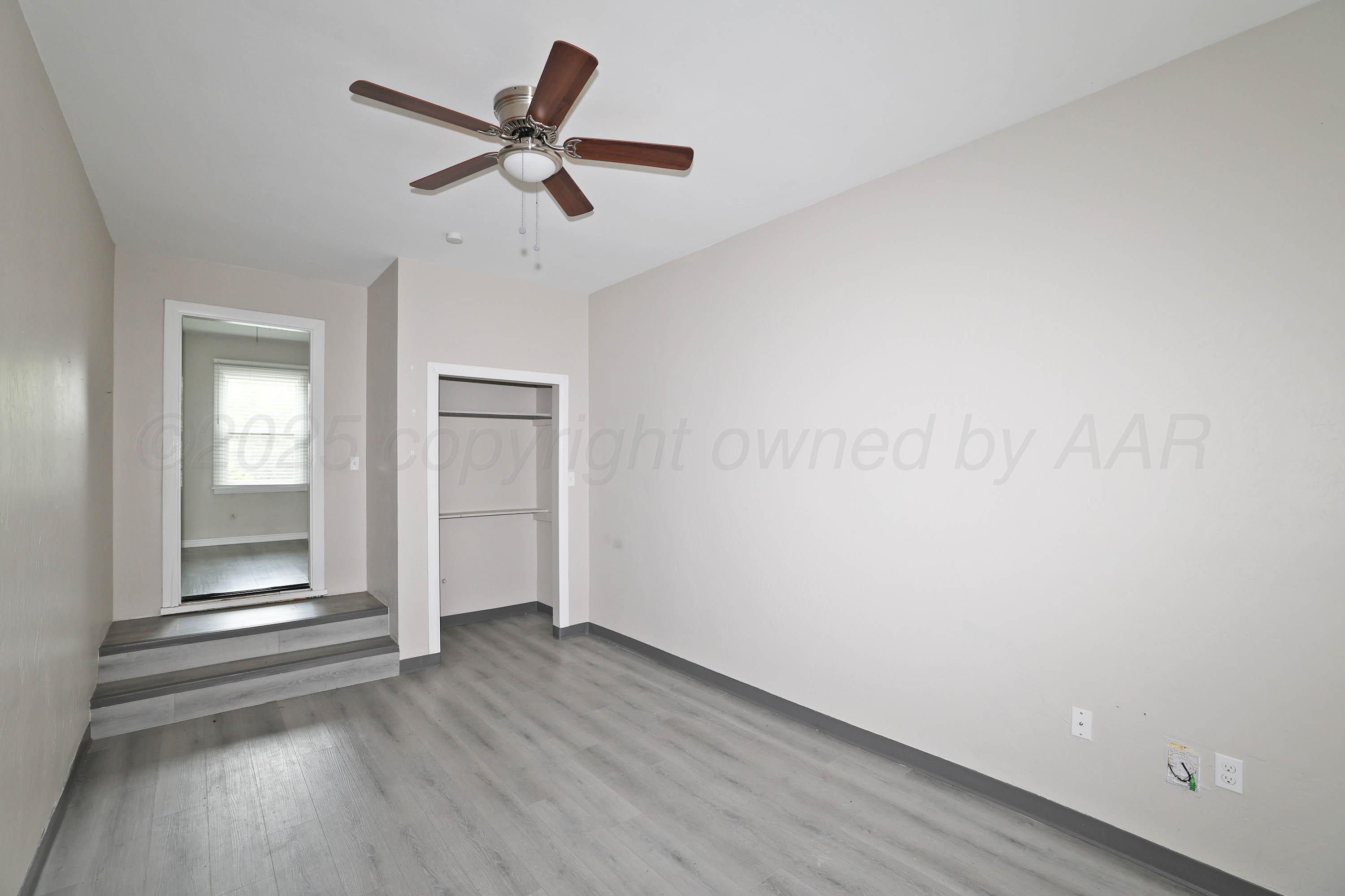 4112 South Tyler Street Amarillo, TX 79110 - Photo 11 of 20 an empty room with wooden floor ceiling fan and windows