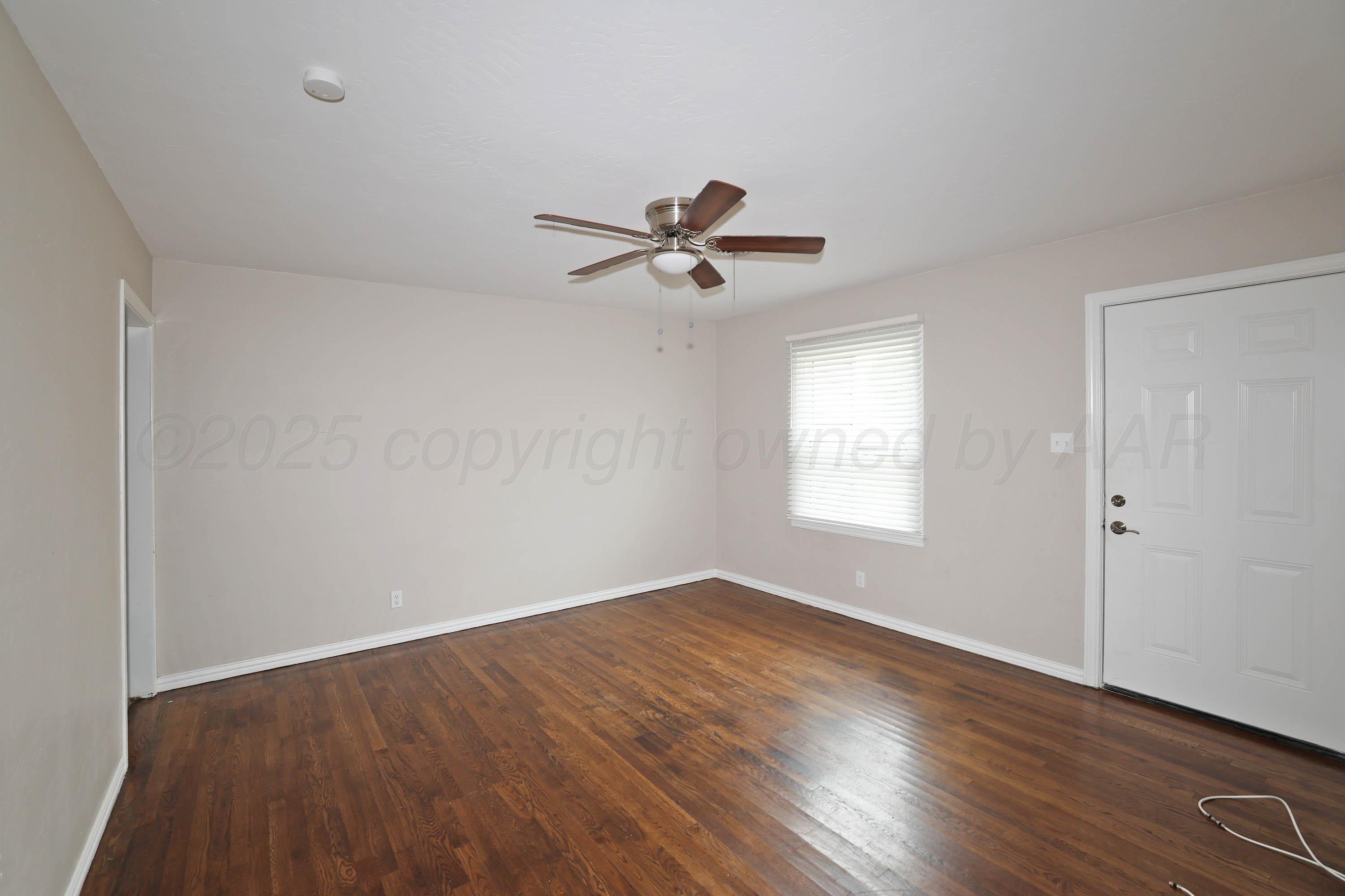 4112 South Tyler Street Amarillo, TX 79110 - Photo 4 of 20 an empty room with wooden floor and ceiling fan