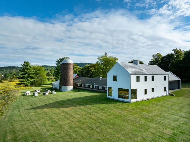a view of a white house with a big yard and large trees