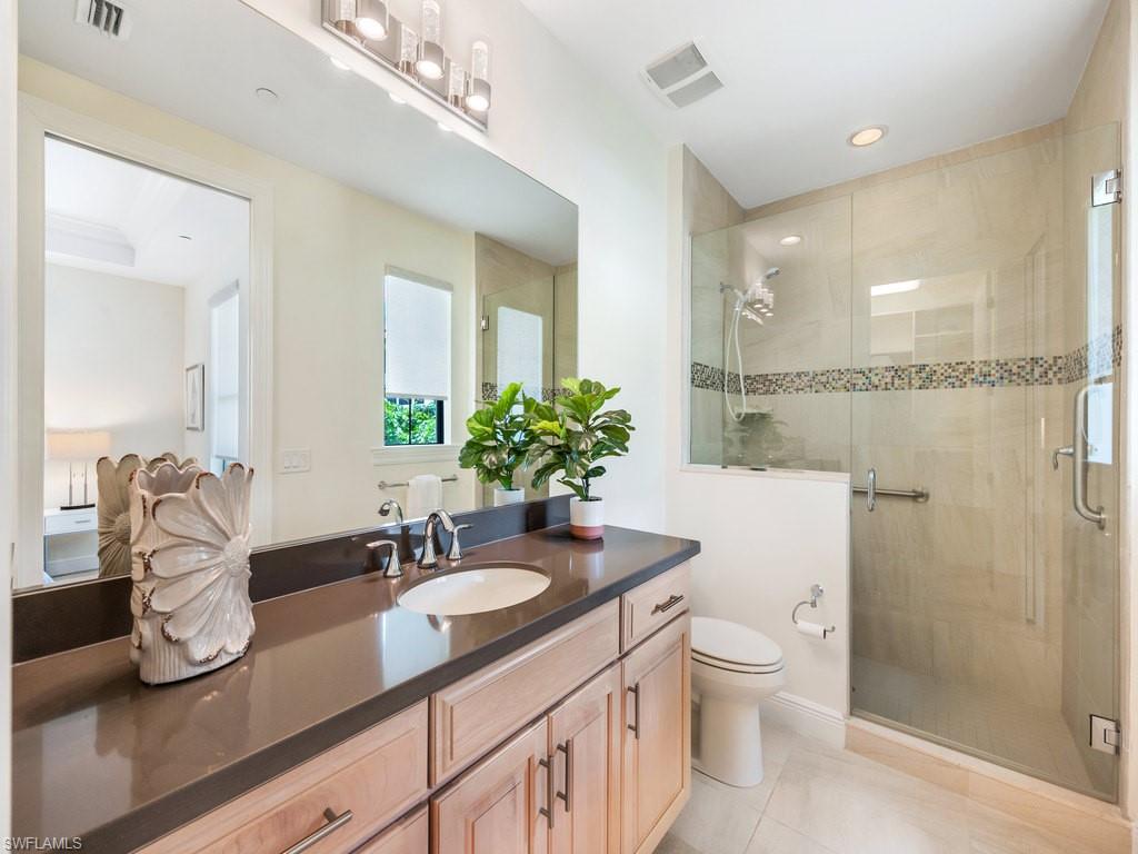 16425 Carrara Way, Unit 101 Naples, FL 34110 - Photo 20 of 21 a bathroom with a granite countertop sink a toilet a mirror and shower