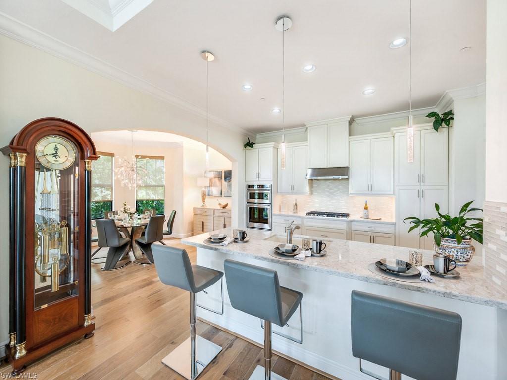 16425 Carrara Way, Unit 101 Naples, FL 34110 - Photo 4 of 21 a kitchen with a table chairs stove and cabinets