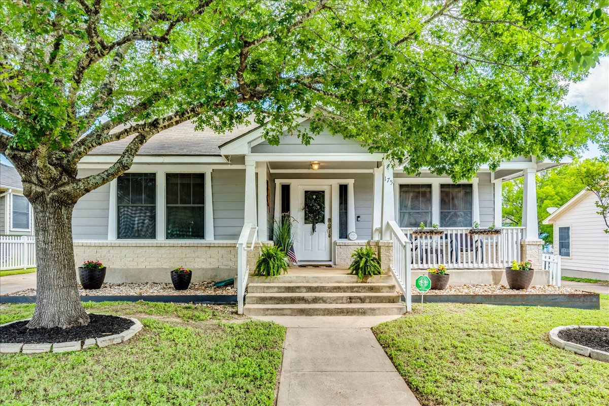 An inviting front porch welcomes guests to this charming residence, shaded by a mature tree.