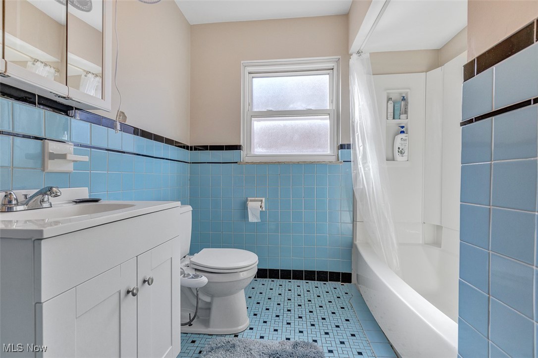 6136 Ridge Road Cleveland, OH 44129 - Photo 25 of 40 Full bath with tile walls, vanity, wainscoting, shower / tub combo with curtain, and light tile patterned floors