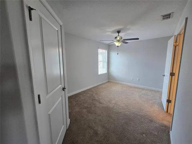 an empty room with windows and a ceiling fan