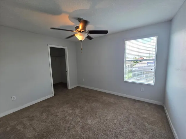 an empty room with a window and a fan