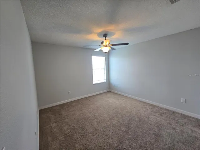 an empty room with a window and a fan