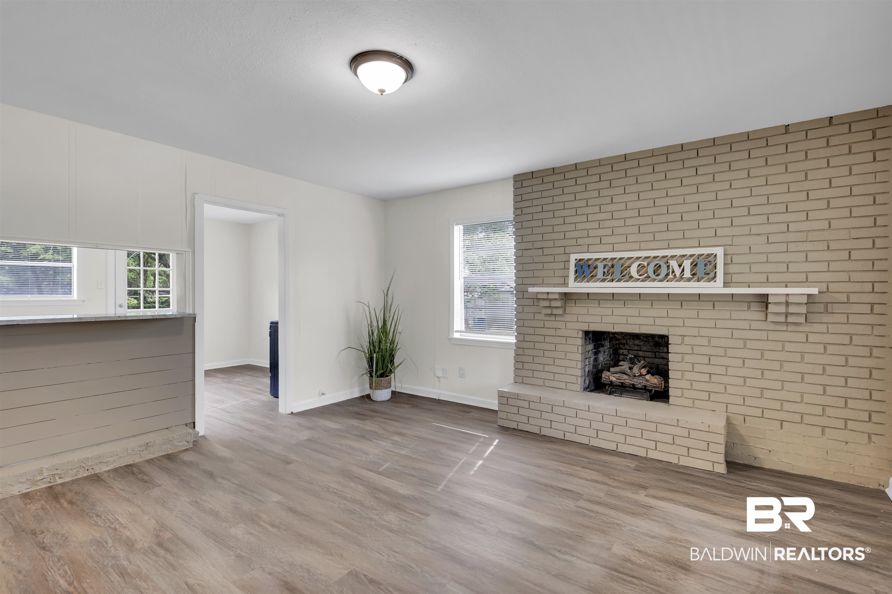 9241 Vallaris Street North Mobile, AL 36608 - Photo 9 of 17 Unfurnished living room with a fireplace, wood finished floors, a wealth of natural light, and baseboards