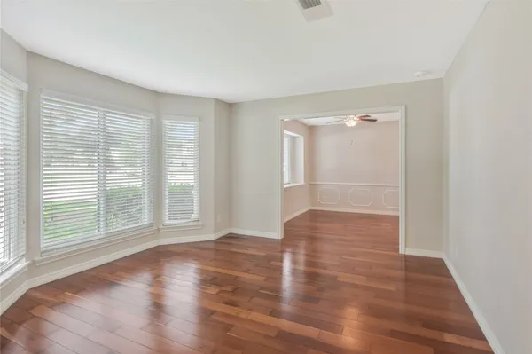 a view of empty room with wooden floor and fan