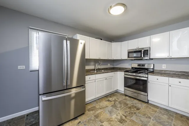 a kitchen with granite countertop a refrigerator stove top oven and sink