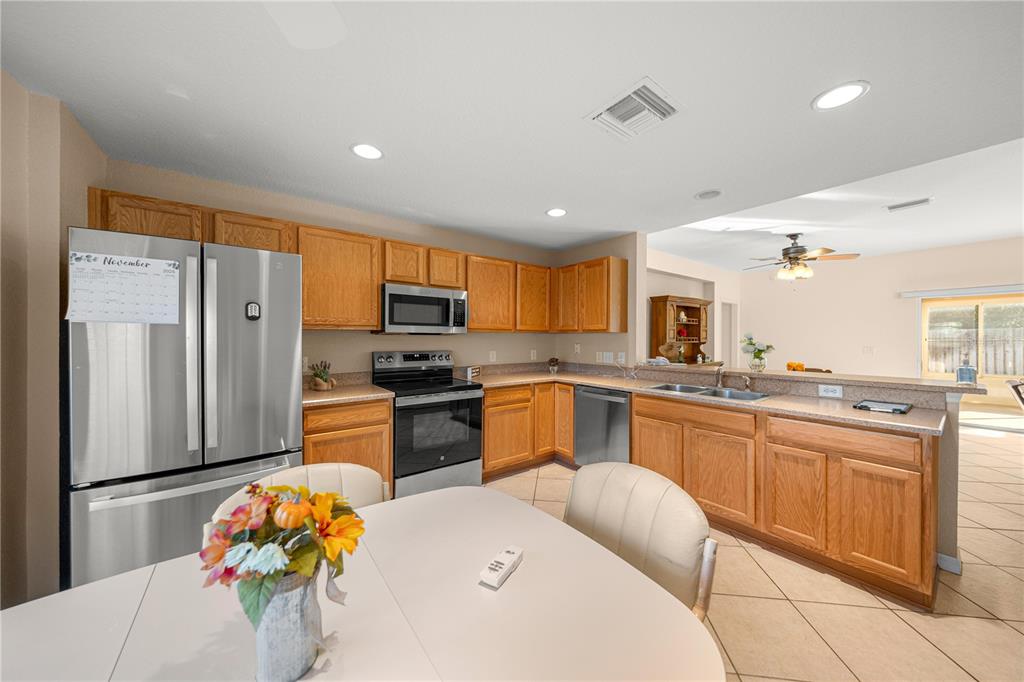 9175 Southeast 118th Loop Summerfield, FL 34491 - Photo 10 of 28 a large kitchen with stainless steel appliances kitchen island granite countertop a refrigerator and a sink