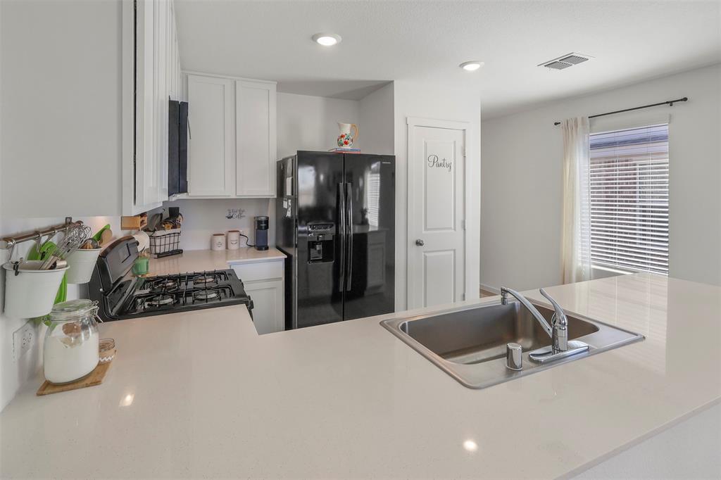 7229 Adderly Road Pilot Point, TX 76258 - Photo 13 of 34 a kitchen with stainless steel appliances granite countertop a sink refrigerator and cabinets
