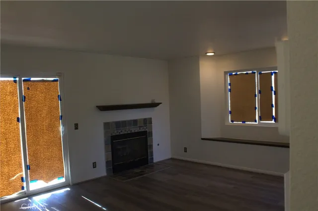 an empty room with wooden floor fireplace and windows
