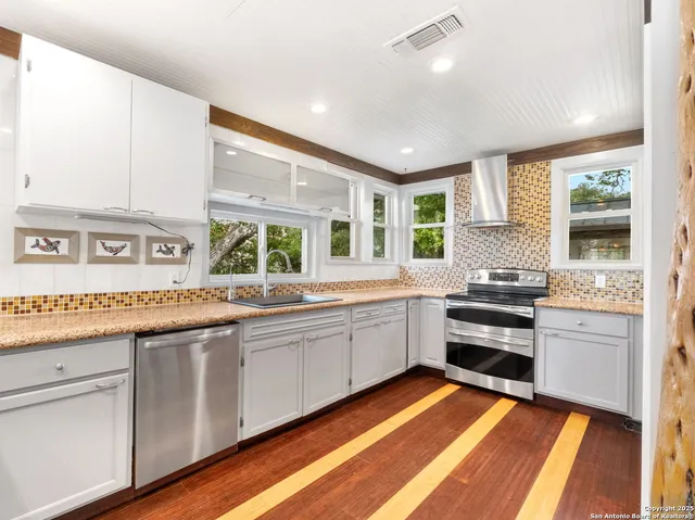 a large kitchen with stainless steel appliances granite countertop a stove and a sink