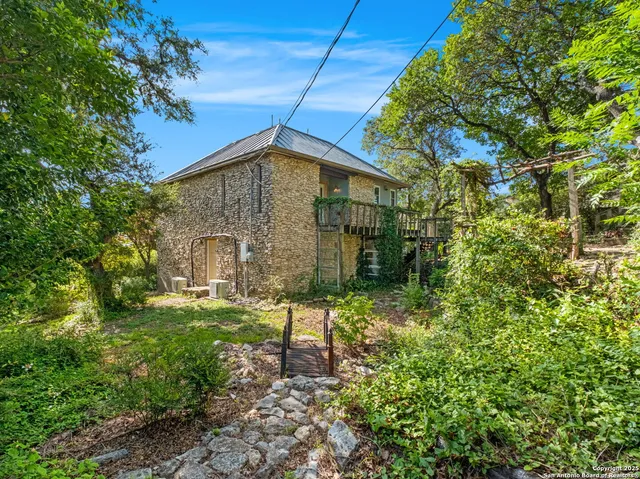 a brick house with a yard plants and large tree