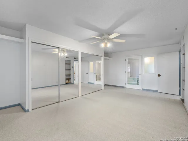 an empty room with a mirror and a fan