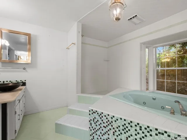 a bathroom with a bathtub sink and mirror