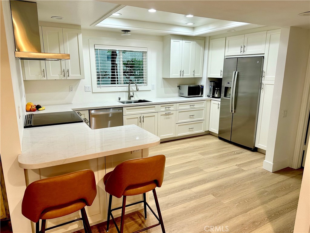 a kitchen with stainless steel appliances white cabinets and wooden floor