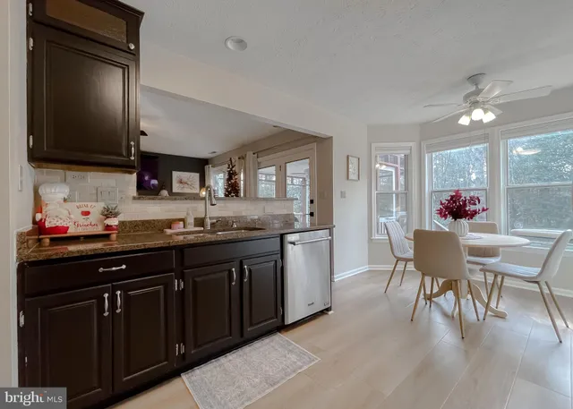 a kitchen with stainless steel appliances granite countertop a refrigerator a sink dishwasher a stove and white cabinets with wooden floor