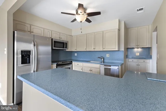 a kitchen with stainless steel appliances granite countertop a sink a stove a refrigerator a washer dryer and cabinets