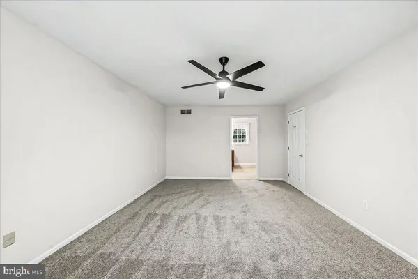 an empty room with a ceiling fan and a window