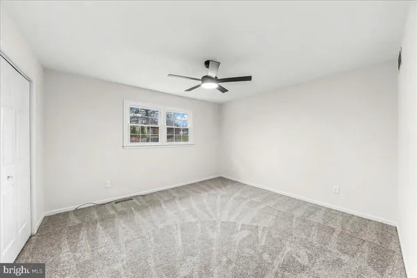 an empty room with a ceiling fan and window