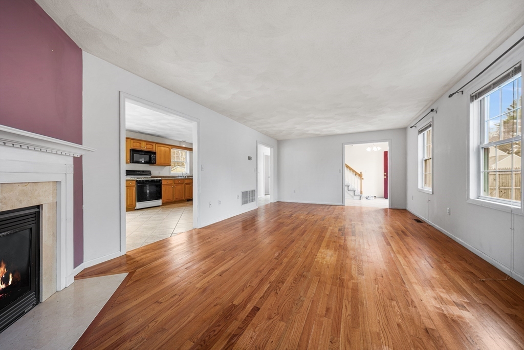 12 Horton Lane Billerica, MA 01821 - Photo 12 of 21 an empty room with wooden floor fireplace and windows
