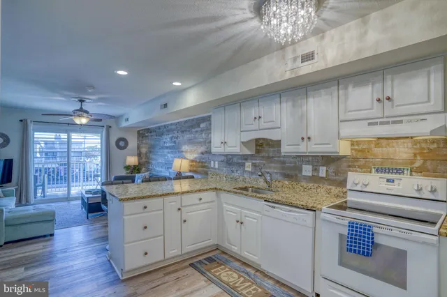 a kitchen with stainless steel appliances granite countertop a refrigerator a stove a sink and white cabinets