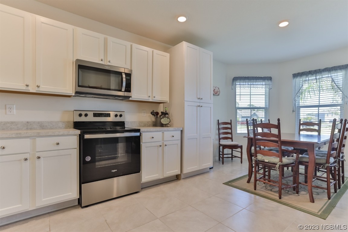 302 Sunset View Drive Edgewater, FL 32141 - Photo 18 of 45 a kitchen with stainless steel appliances granite countertop a stove a sink a microwave a dining table and chairs