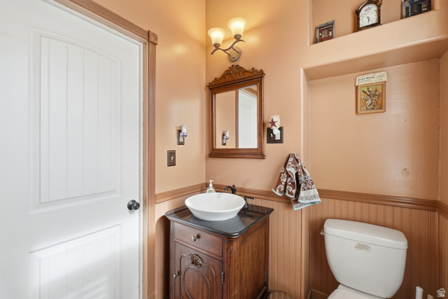 5264 West 5500th Street South Hooper, UT 84315 - Photo 25 of 38 Bathroom featuring a white vessel sink, dark wood vanity with a black countertop, beadboard wainscoting, and a wall-mounted light fixture