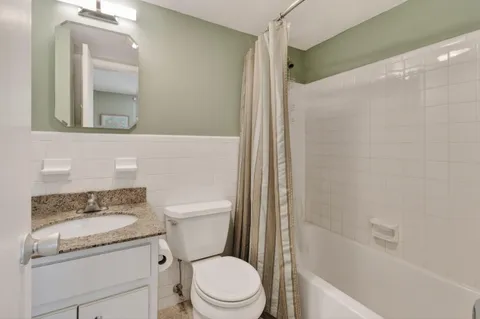 a bathroom with a granite countertop sink toilet mirror and shower