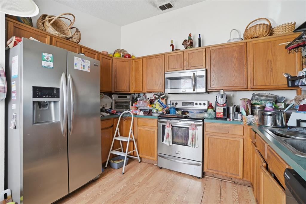 1650 East Welch Road Apopka, FL 32712 - Photo 13 of 29 a kitchen with stainless steel appliances granite countertop a refrigerator a stove and a sink with wooden floor