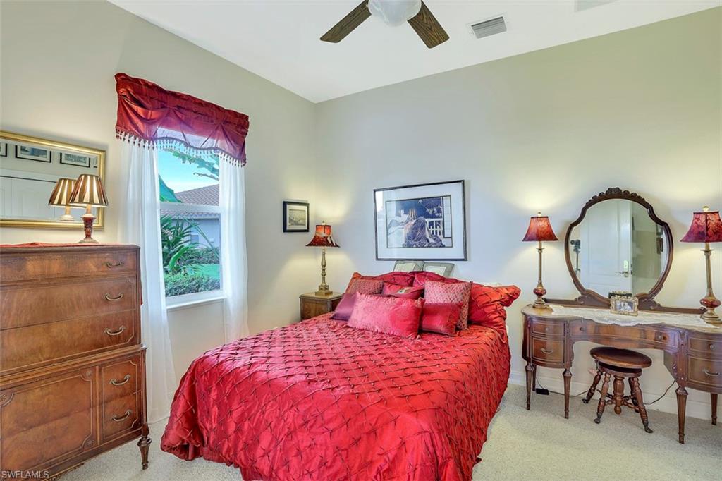 134 Windward Cay Naples, FL 34114 - Photo 31 of 35 a bedroom with a bed a desk and chair with a mirror