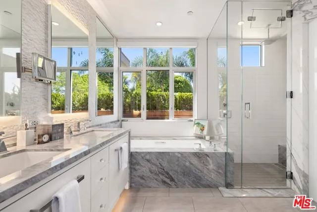a bathroom with a granite countertop double vanity sink a mirror and a bathtub