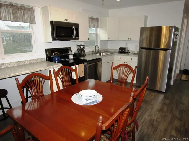a kitchen with a dining table chairs refrigerator and microwave
