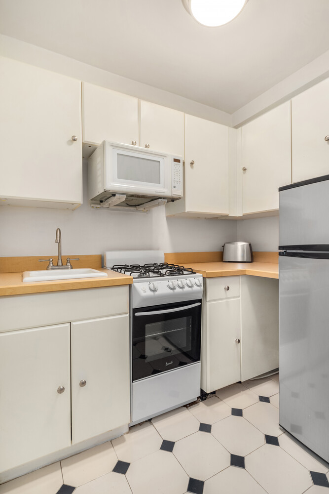 200 West 79th Street, Unit 16S Manhattan, NY 10024 - Photo 5 of 9 a kitchen with granite countertop white cabinets and white appliances