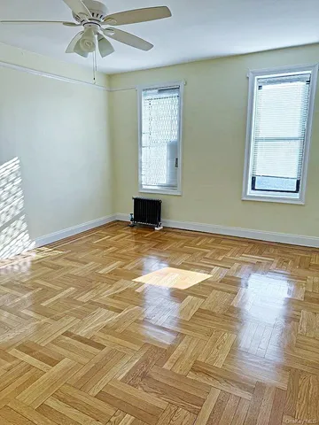 a view of an empty room with window and wooden floor