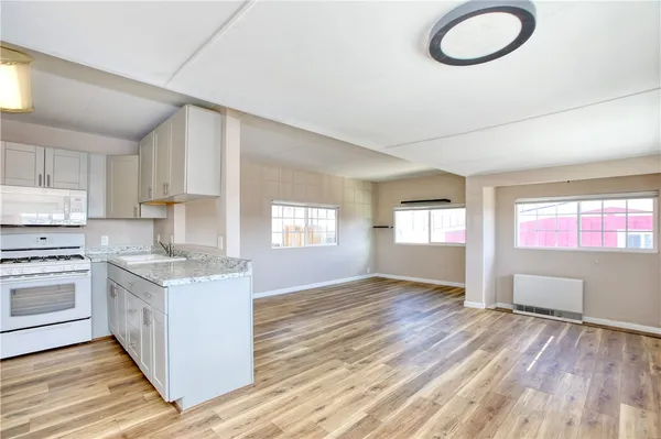 a kitchen with stainless steel appliances granite countertop a stove a sink dishwasher and a refrigerator with wooden floors