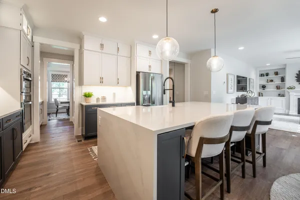 a kitchen with stainless steel appliances kitchen island granite countertop a table chairs and a refrigerator