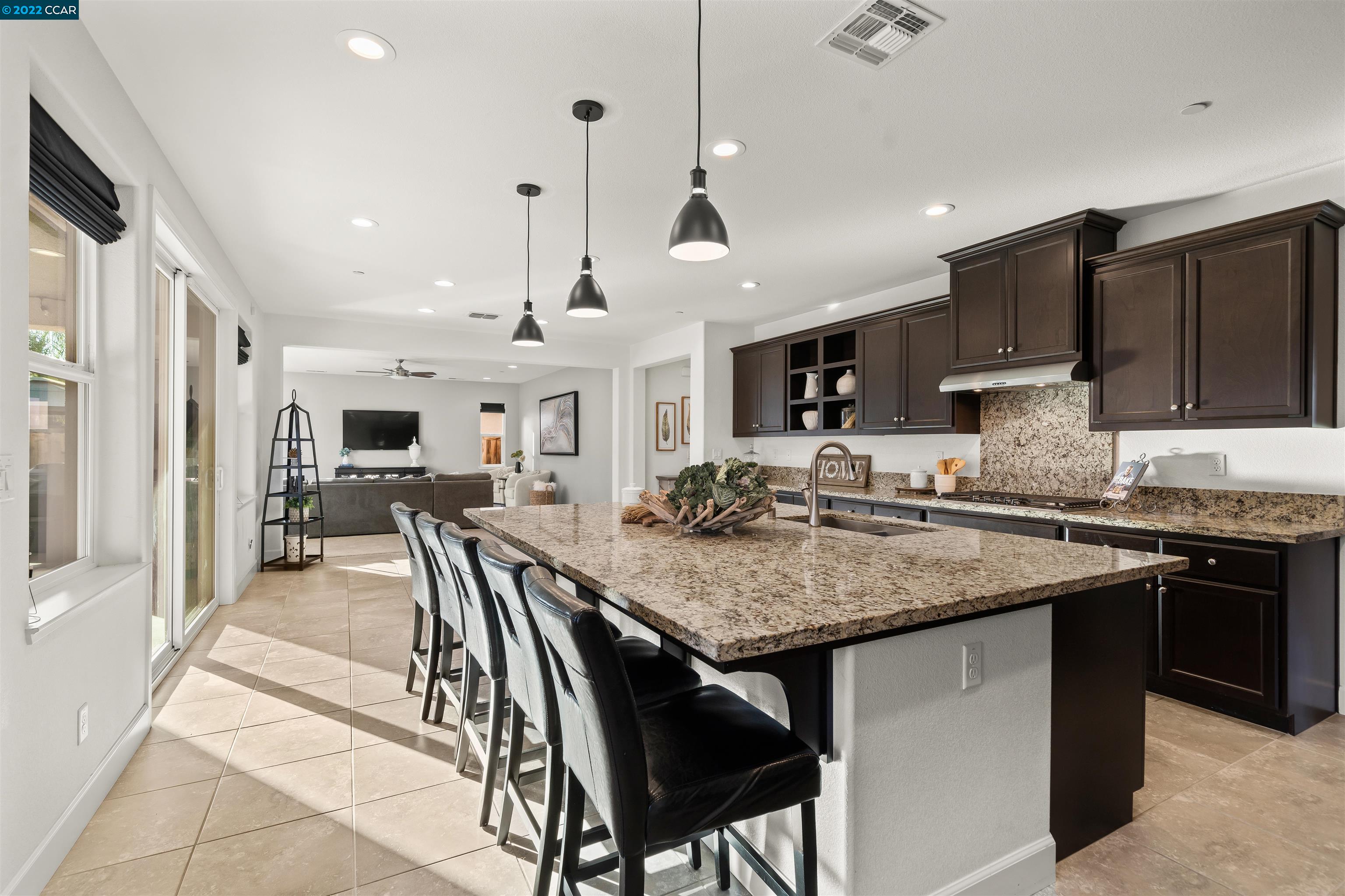 2468 Flag Stop Way Tracy, CA 95377 - Photo 5 of 36 a kitchen with stainless steel appliances granite countertop a stove top oven a sink a dining table and chairs with wooden floor