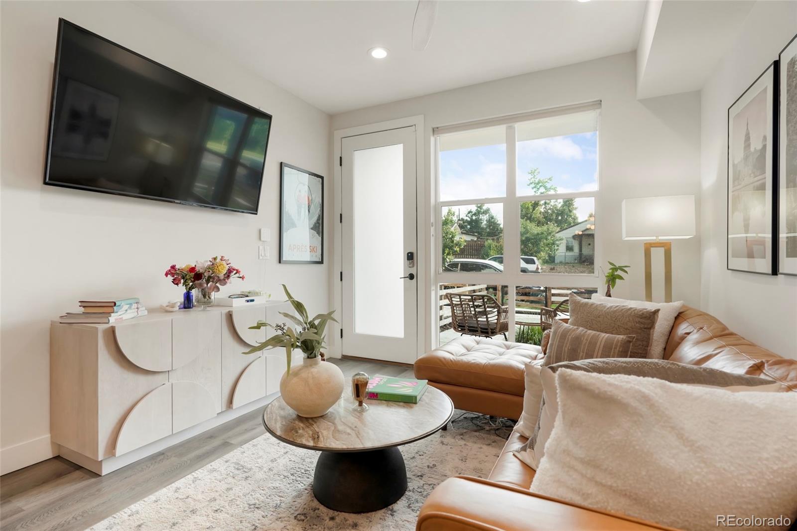 1082 King Street Denver, CO 80204 - Photo 3 of 21 a living room with furniture a flat screen tv and a floor to ceiling window
